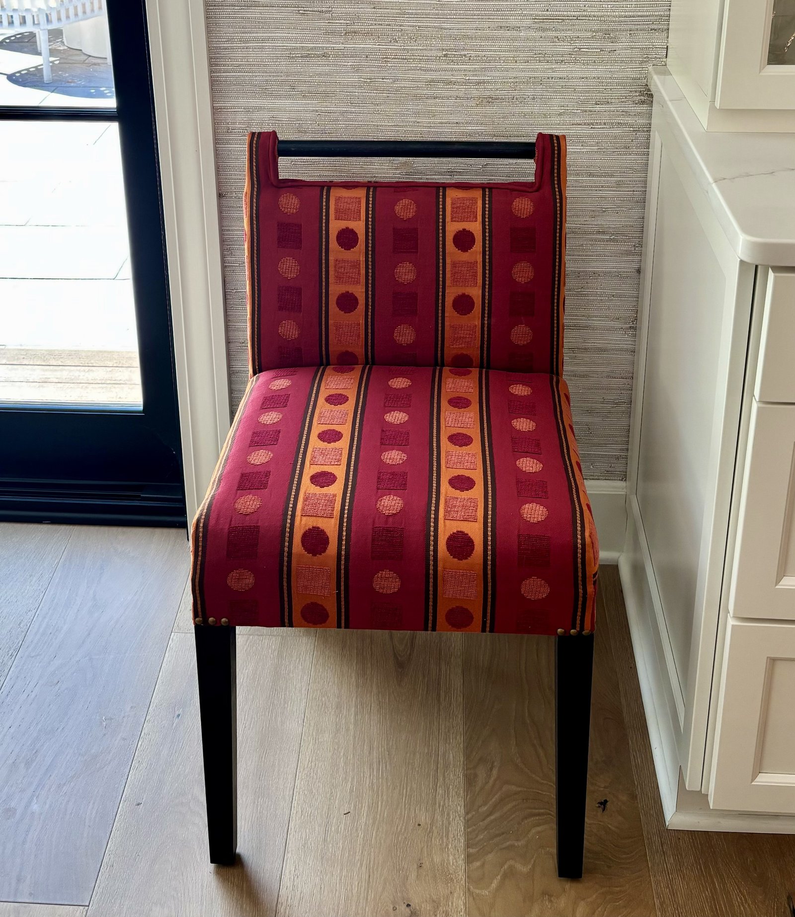 Handcrafted dining chair upholstered in a bold red and orange striped fabric